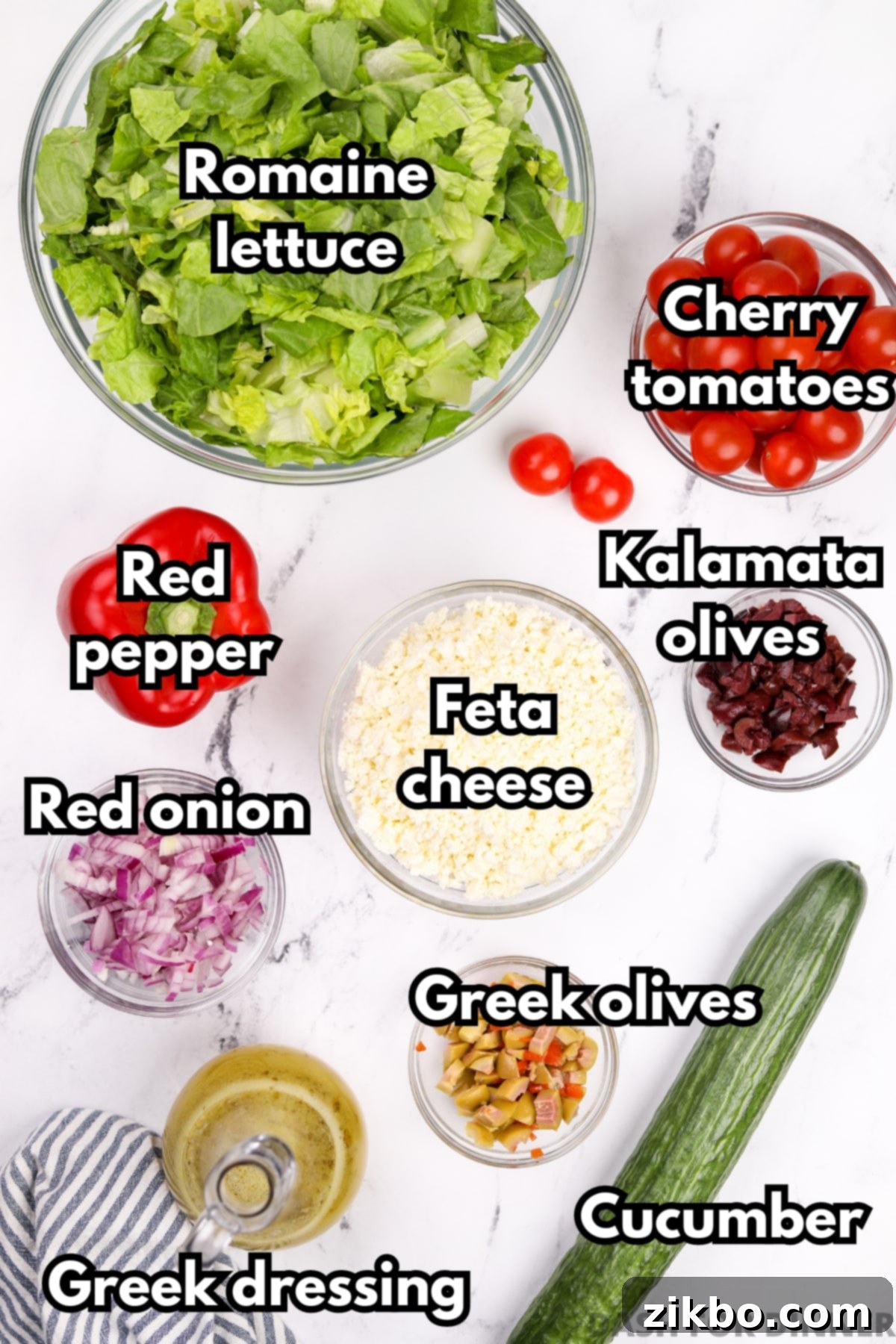 The Perfect Greek Chopped Salad 3 The vibrant ingredients laid out for making Greek chopped salad, including a block of feta cheese, fresh tomatoes, crisp cucumber, and a bottle of Greek dressing.