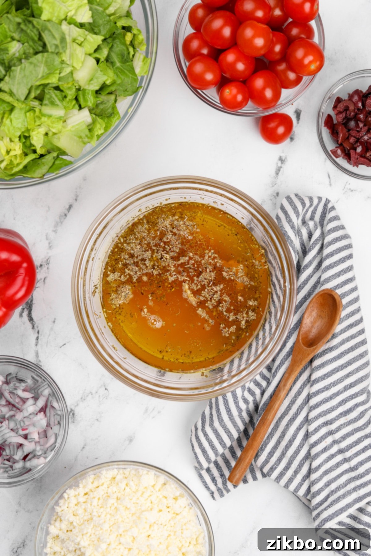 The Perfect Greek Chopped Salad 4 A collection of dressing ingredients including olive oil, red wine vinegar, lemon, and spices in small bowls.