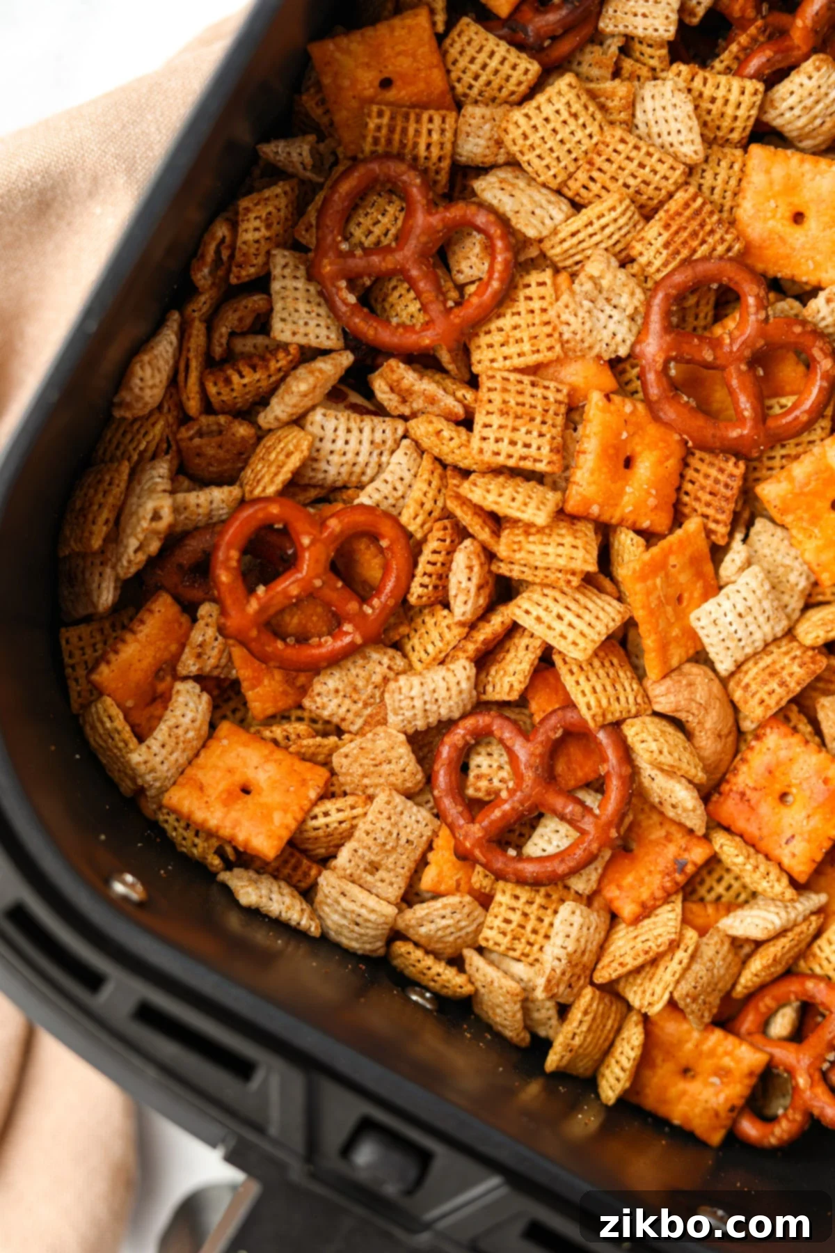 An air fryer basket filled with homemade Chex mix.