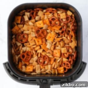 An air fryer basket filled with Chex mix.