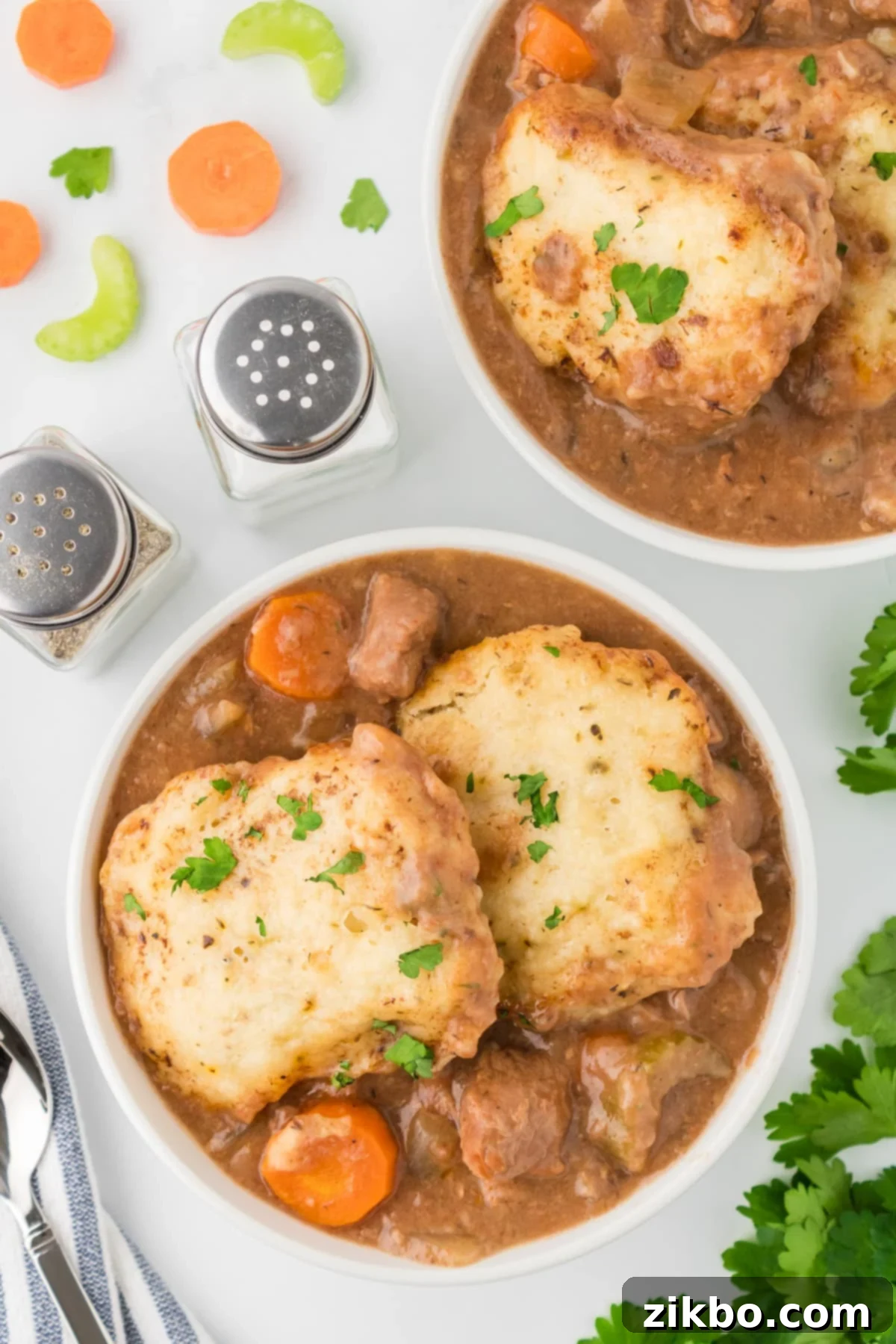Hearty Slow Cooker Beef Stew with Tender Dumplings 2 A bowl of beef stew topped with two dumplings, garnished with parsley.