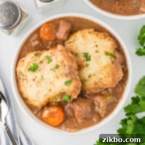 Hearty Slow Cooker Beef Stew with Tender Dumplings 17 A white bowl filled with beef stew and topped with homemade dumplings.