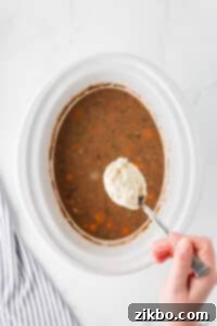 Dropping dumpling dough into a slow cooker filled with beef stew.