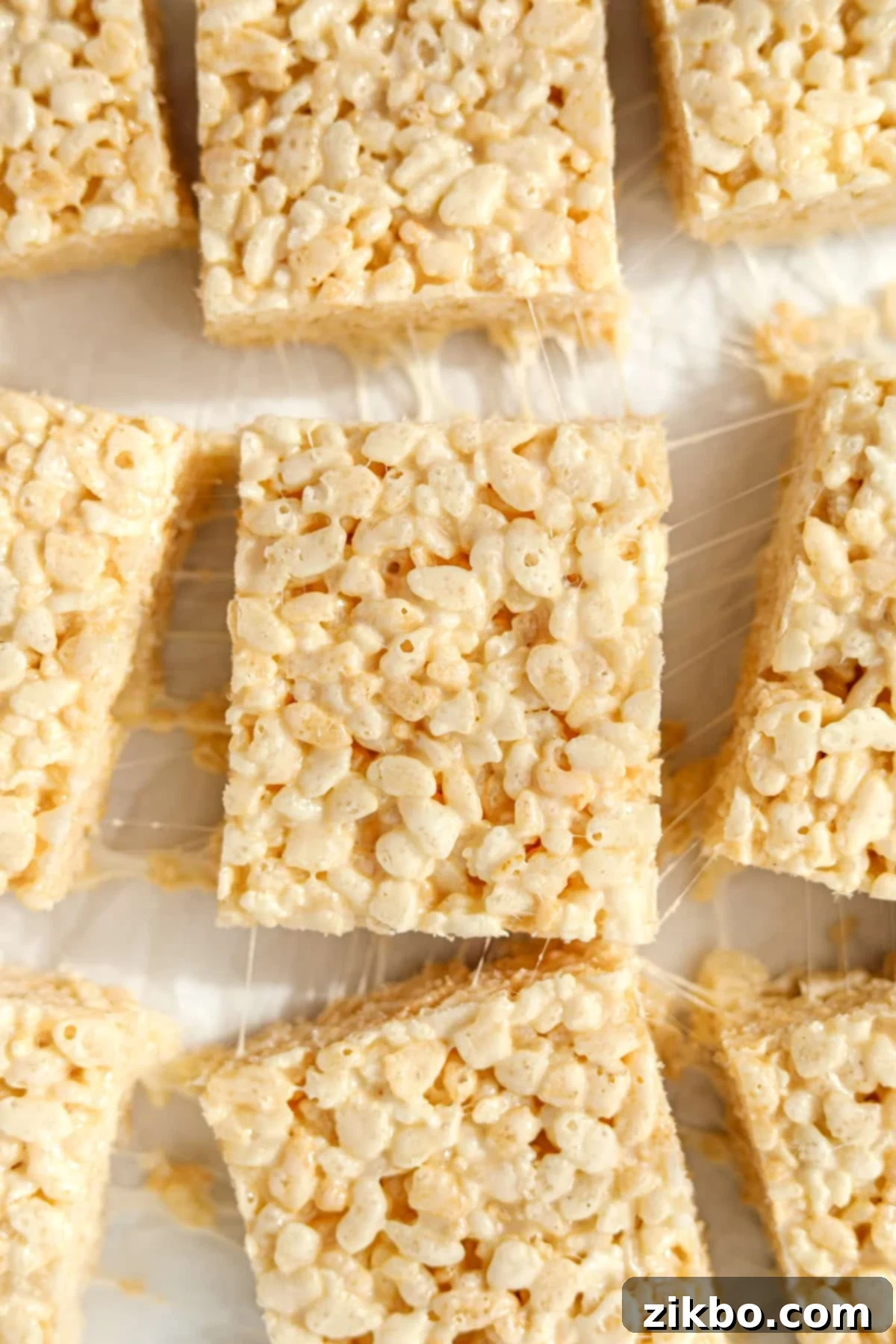 Crispy Sweet Squares 2 Perfectly sliced, extra gooey Rice Krispie treats arranged on a sheet of white parchment paper, ready to be enjoyed.