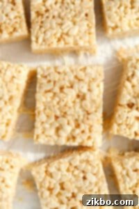 Cereal treats that have been sliced on a sheet of white parchment paper.