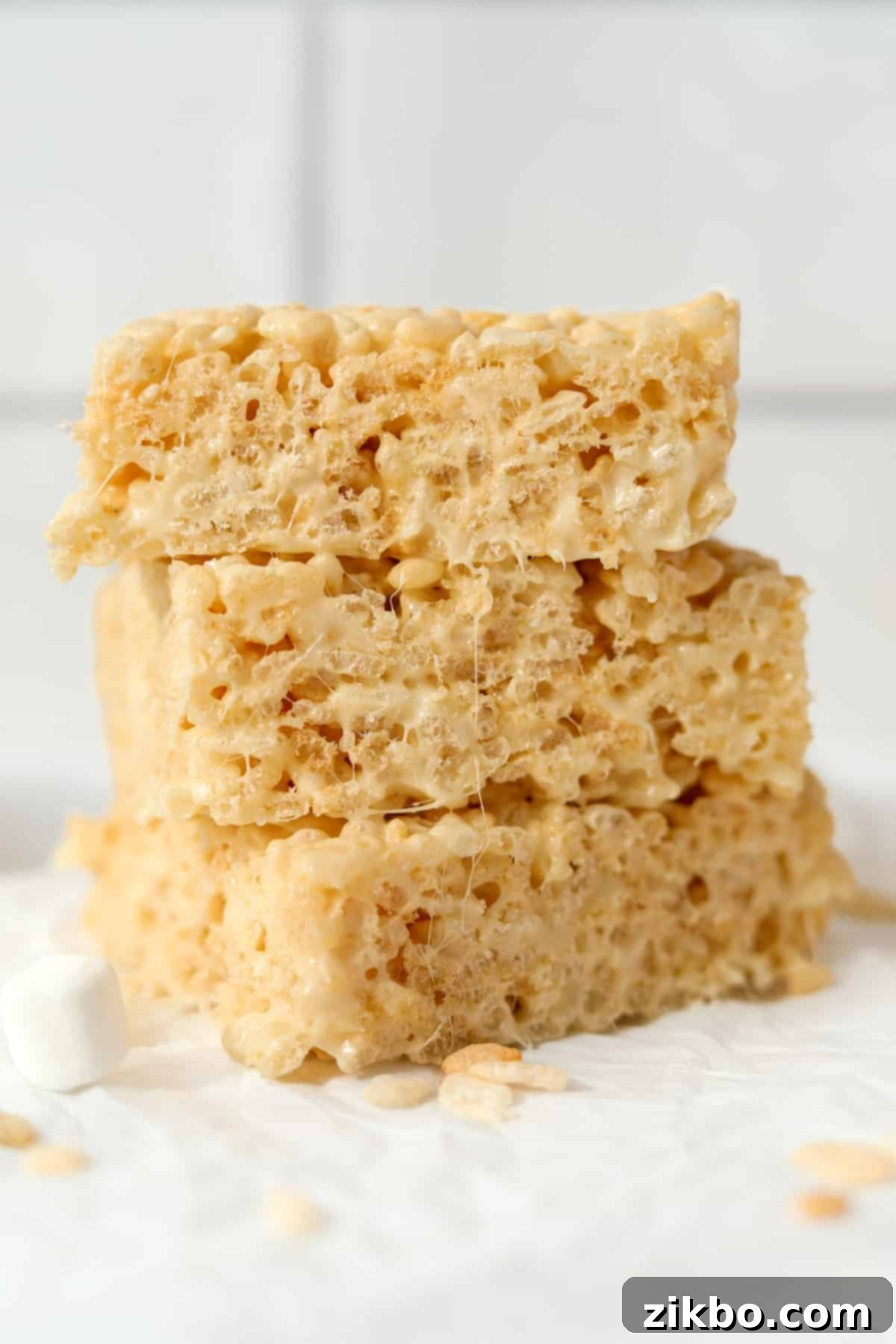 Crispy Sweet Squares 10 A beautiful stack of three golden-brown Rice Krispie treats artfully arranged on a clean white countertop, highlighting their inviting texture.