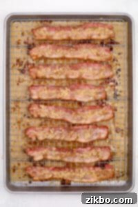Half cooked bacons strips being topped with brown sugar.
