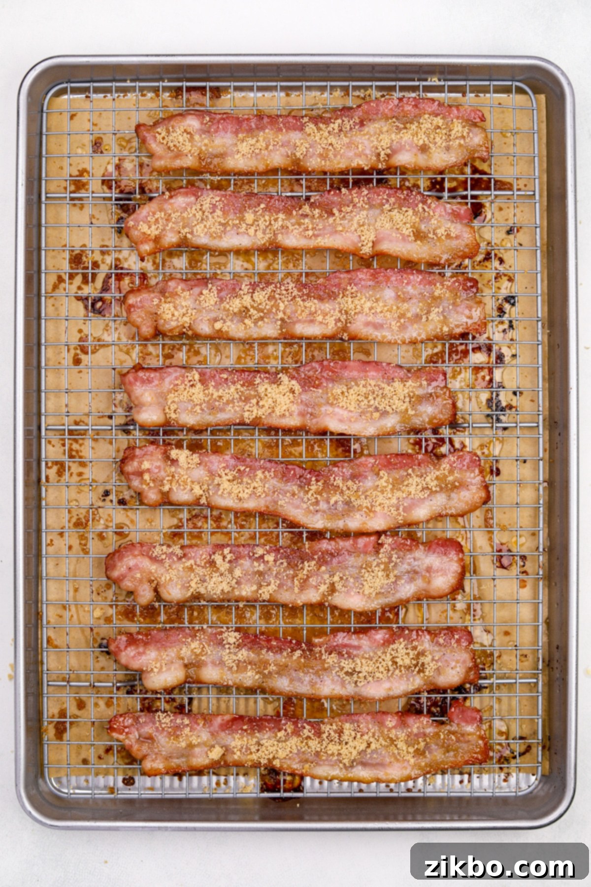 Millionaire's Bacon 8 Partially cooked bacon strips, already glistening, are being topped with the remaining brown sugar mixture after being flipped.