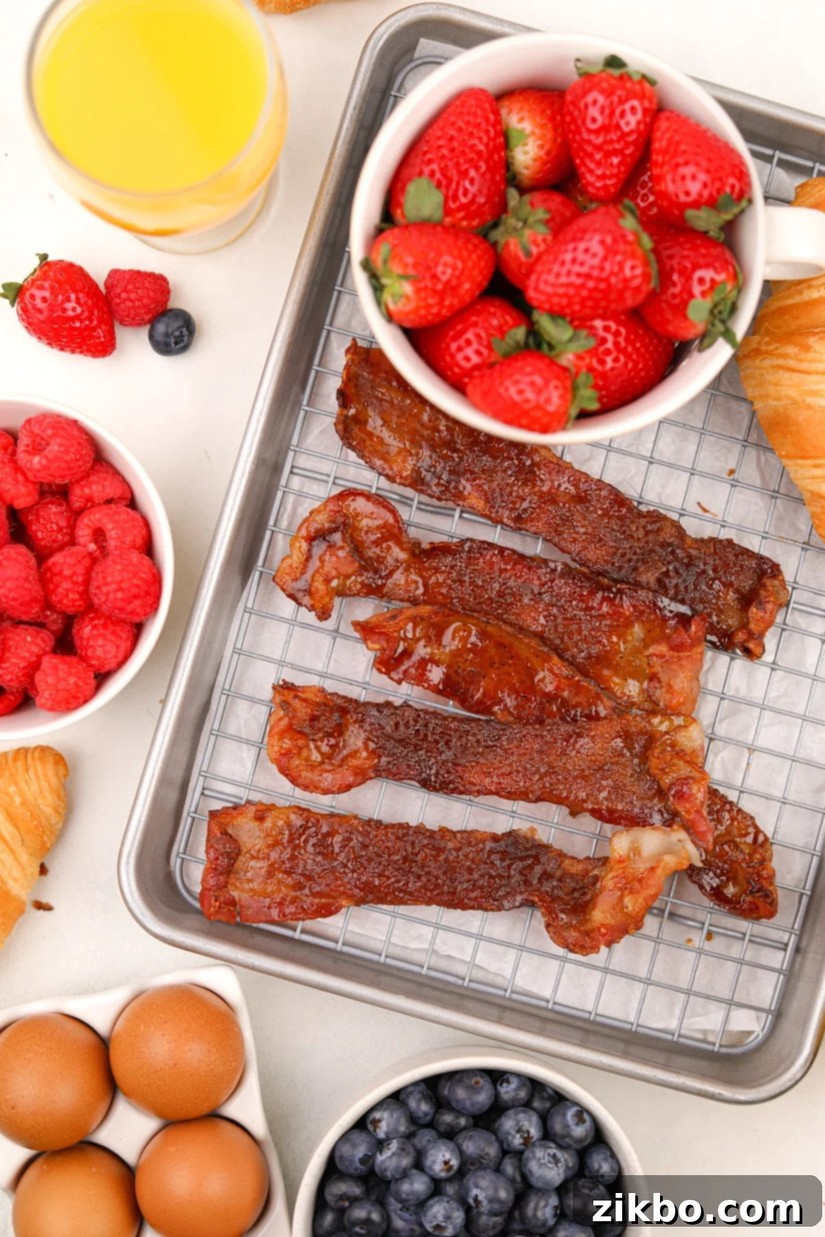 Sweet and Crispy Air Fryer Bacon Bliss 6 Several slices of candied bacon on a wire baking rack, with small bowls of berries all around.