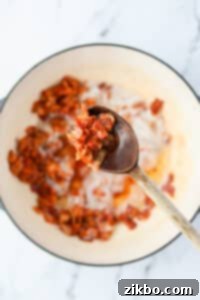 A wooden spoon holding up cooked crispy bacon pieces.