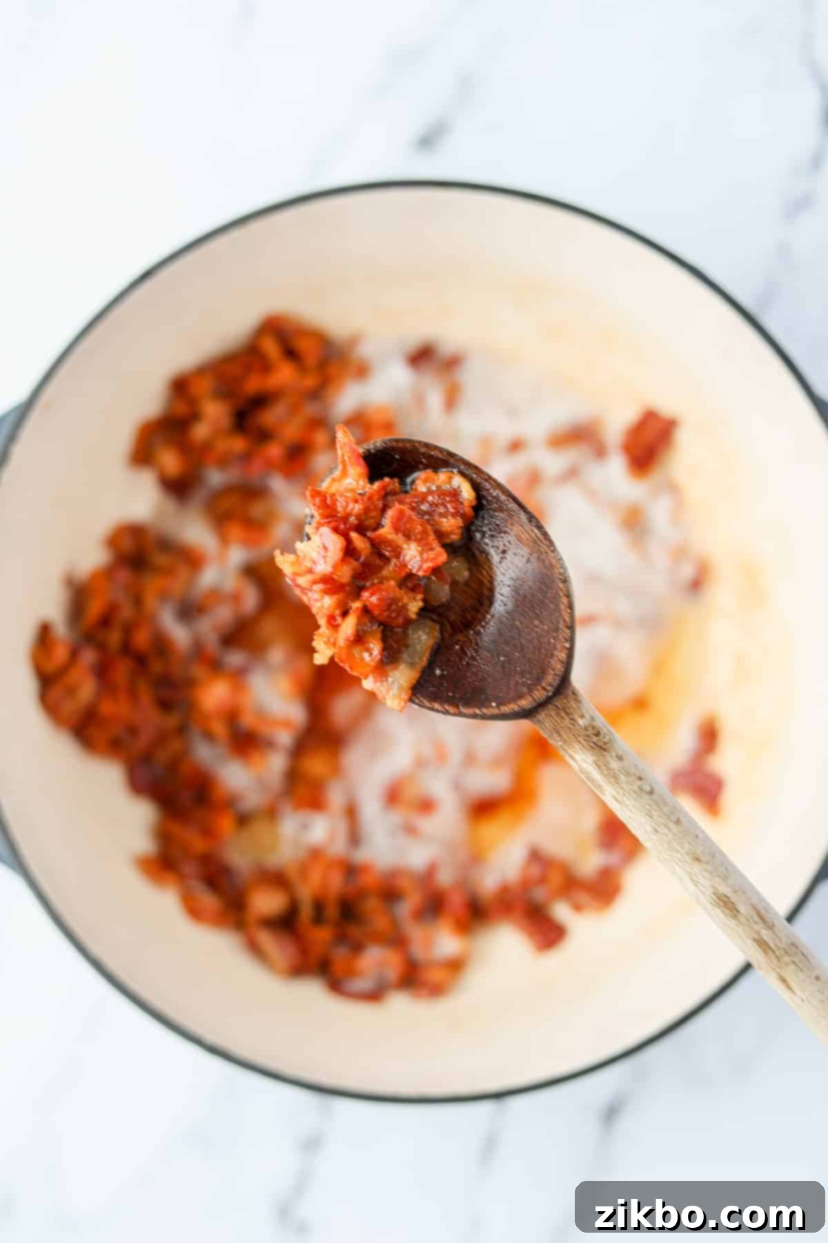 A wooden spoon holding up cooked crispy bacon pieces.