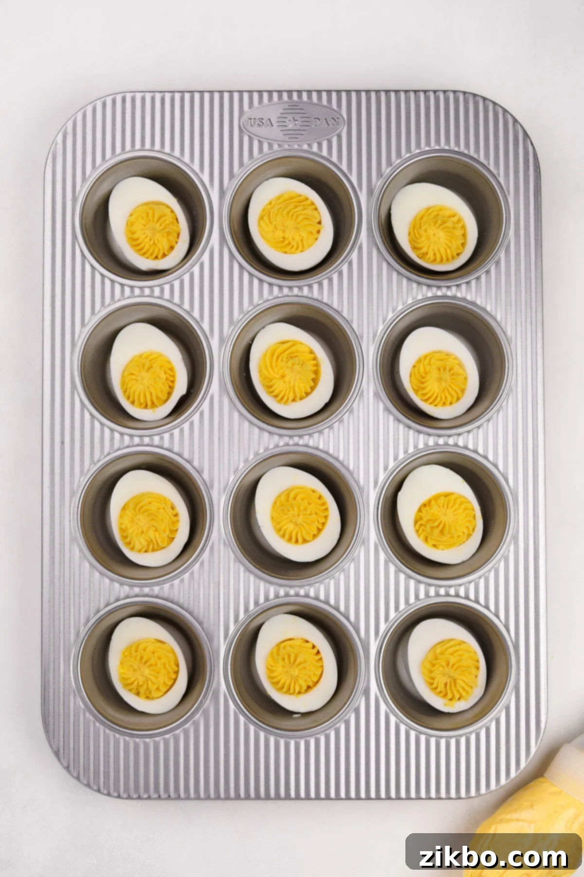 A muffin pan with a deviled egg in each well.