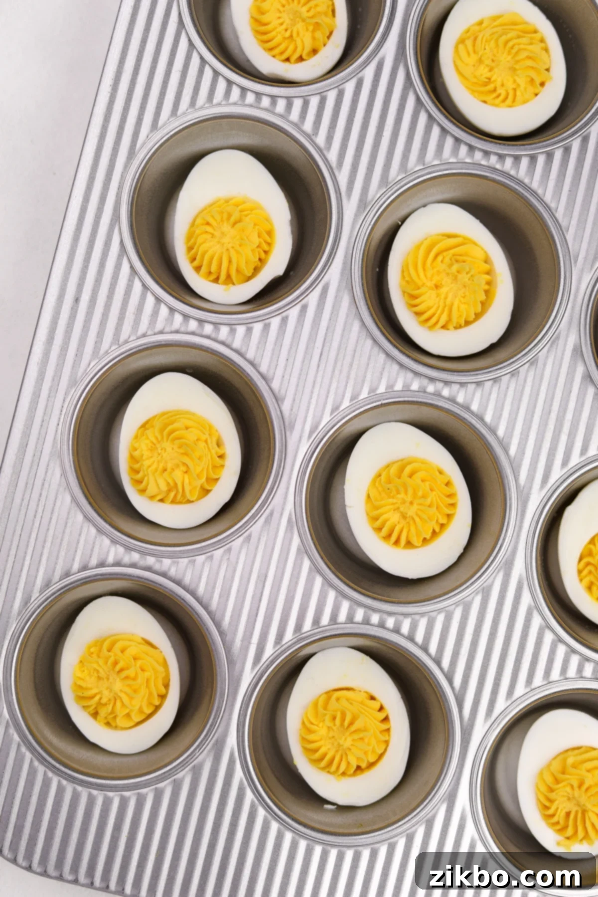 A muffin pan with a deviled egg in each well.