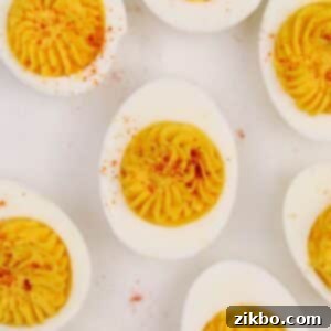 Deviled egg halves on a grey background, sprinkled with paprika.