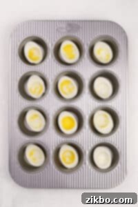 A muffin pan with cooked egg white halves in it.