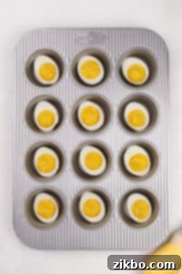 A muffin pan with a deviled egg in each well.