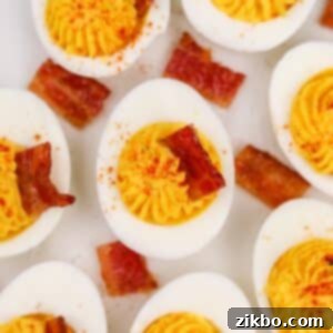 8 deviled egg halves topped with a square of bacon.