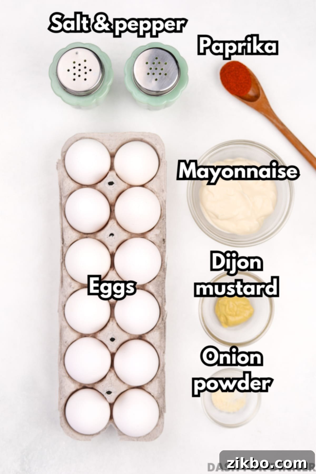 The essential ingredients for deviled eggs, including mayonnaise, Dijon mustard, salt, pepper, and paprika, laid out on a wooden surface.
