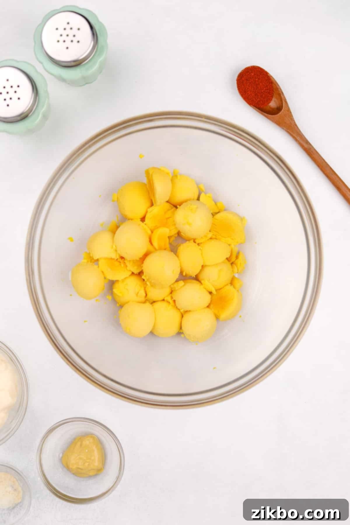 Bright yellow egg yolks neatly scooped into a large mixing bowl, ready to be mashed for the deviled egg filling.