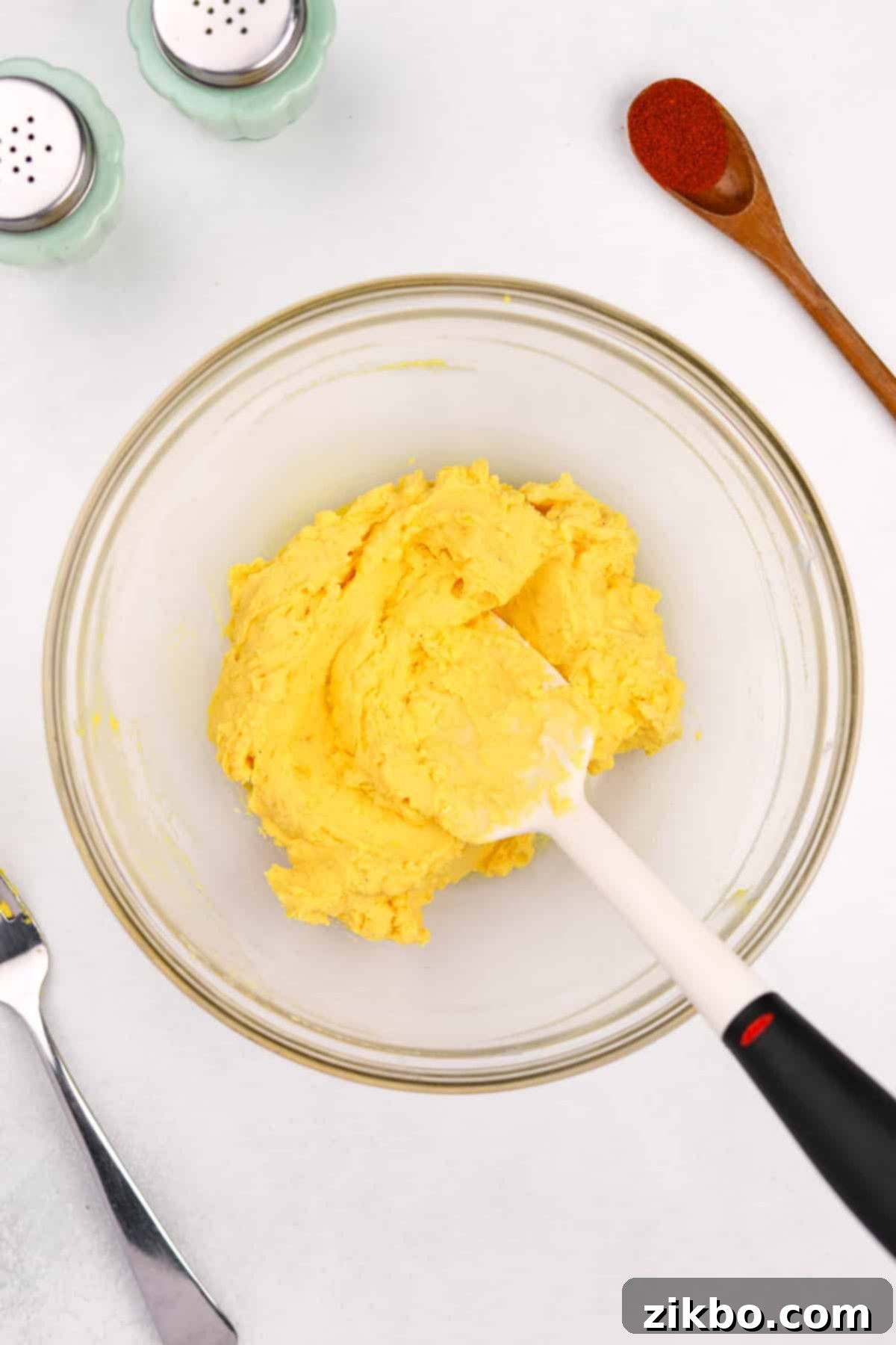The creamy egg yolk mixture being stirred to a smooth consistency in a bowl.