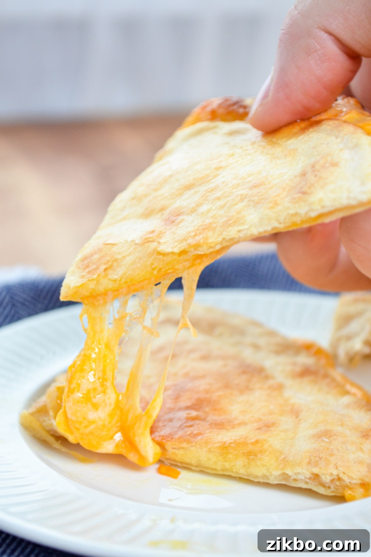 Two freshly made, golden brown Air Fryer Quesadillas, stacked on a plate.