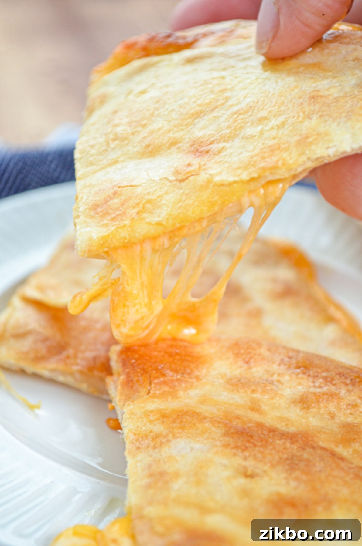 A stack of cheese quesadilla triangles, with one being pulled apart showing melted cheese.