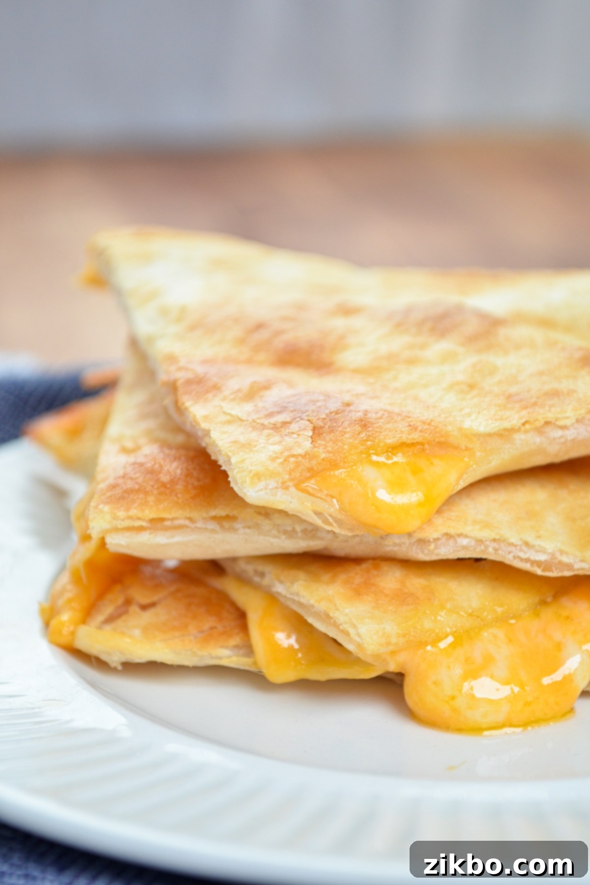 A stack of three golden brown air fryer cheese quesadilla triangles.