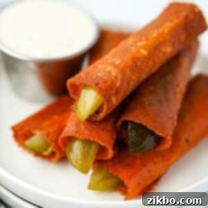 A stack of cheesy fried pickles with a small container of ranch dressing in the background.