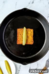 Placing a pickle spear in the middle of a slice of melted cheese.