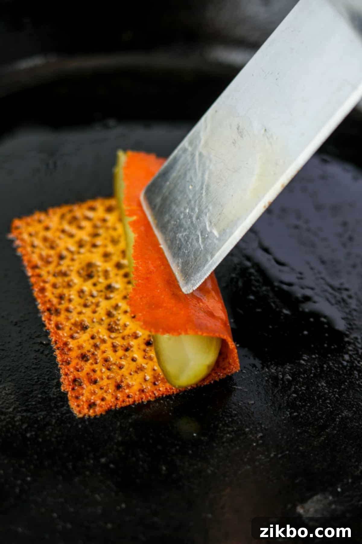 Rolling crispy cheese over a pickle spear.