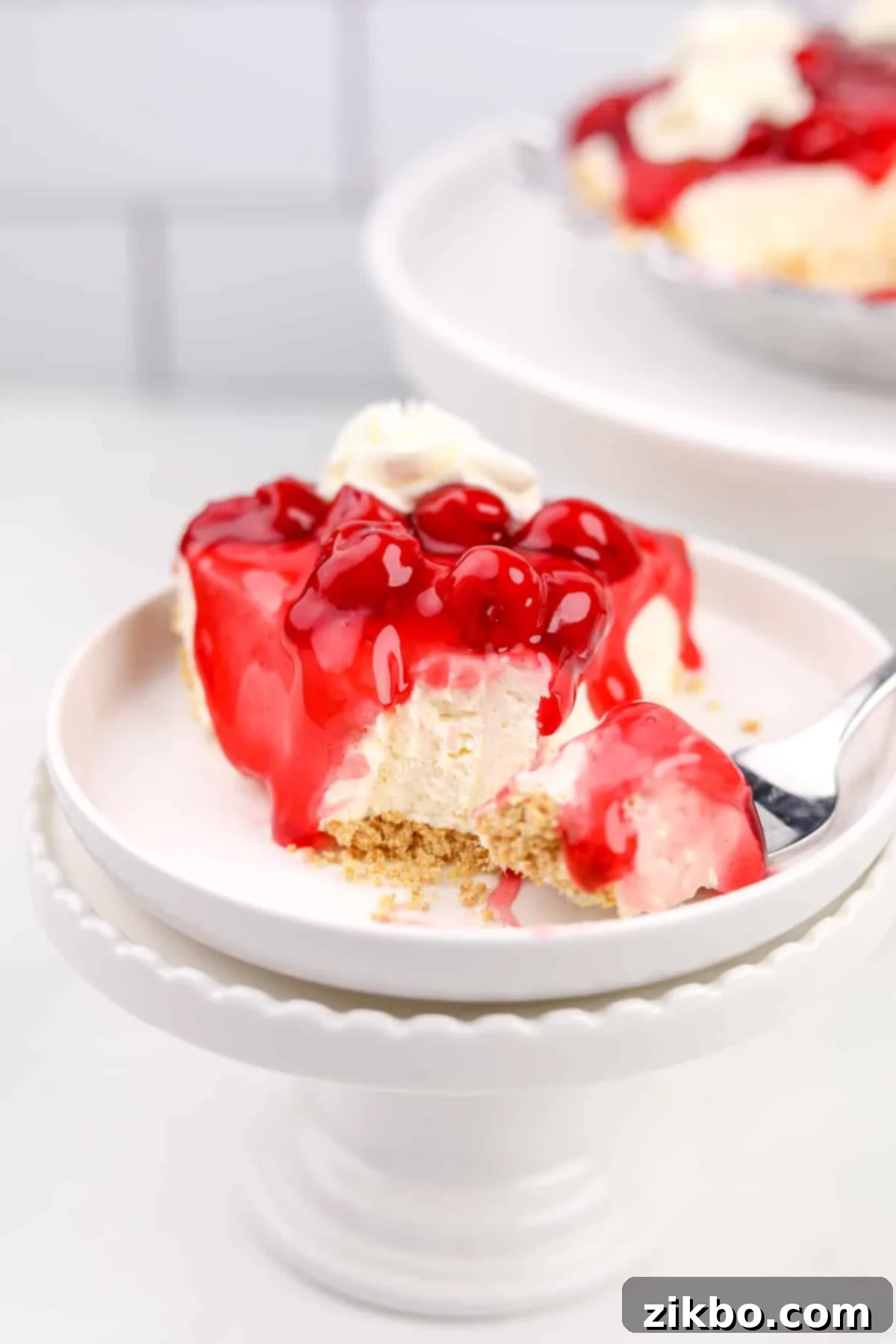 A perfectly sliced no-bake cherry cheesecake, ready to be enjoyed, with a fork beside it.