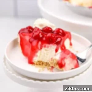 A slice of creamy no-bake cheesecake topped with a glistening cherry glaze, showcasing its delicious texture.
