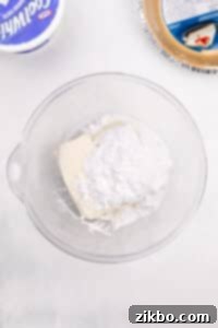 A bowl with cream cheese and powdered sugar in it.