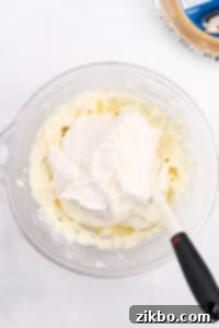 Adding thawed whipped topping to a cream cheese filling.