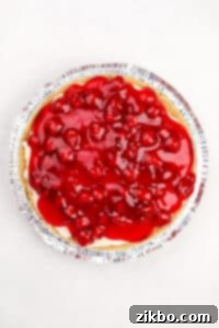 A cheesecake pie topped with cherry pie filling.