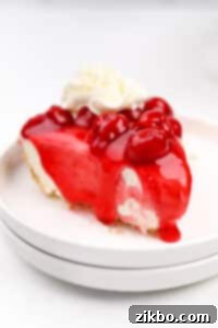 A slice of cheesecake topped with cherry topping and whipped cream.