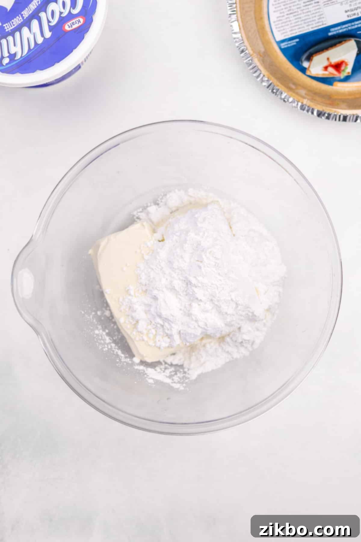 A large mixing bowl containing softened cream cheese and powdered sugar, ready for blending.