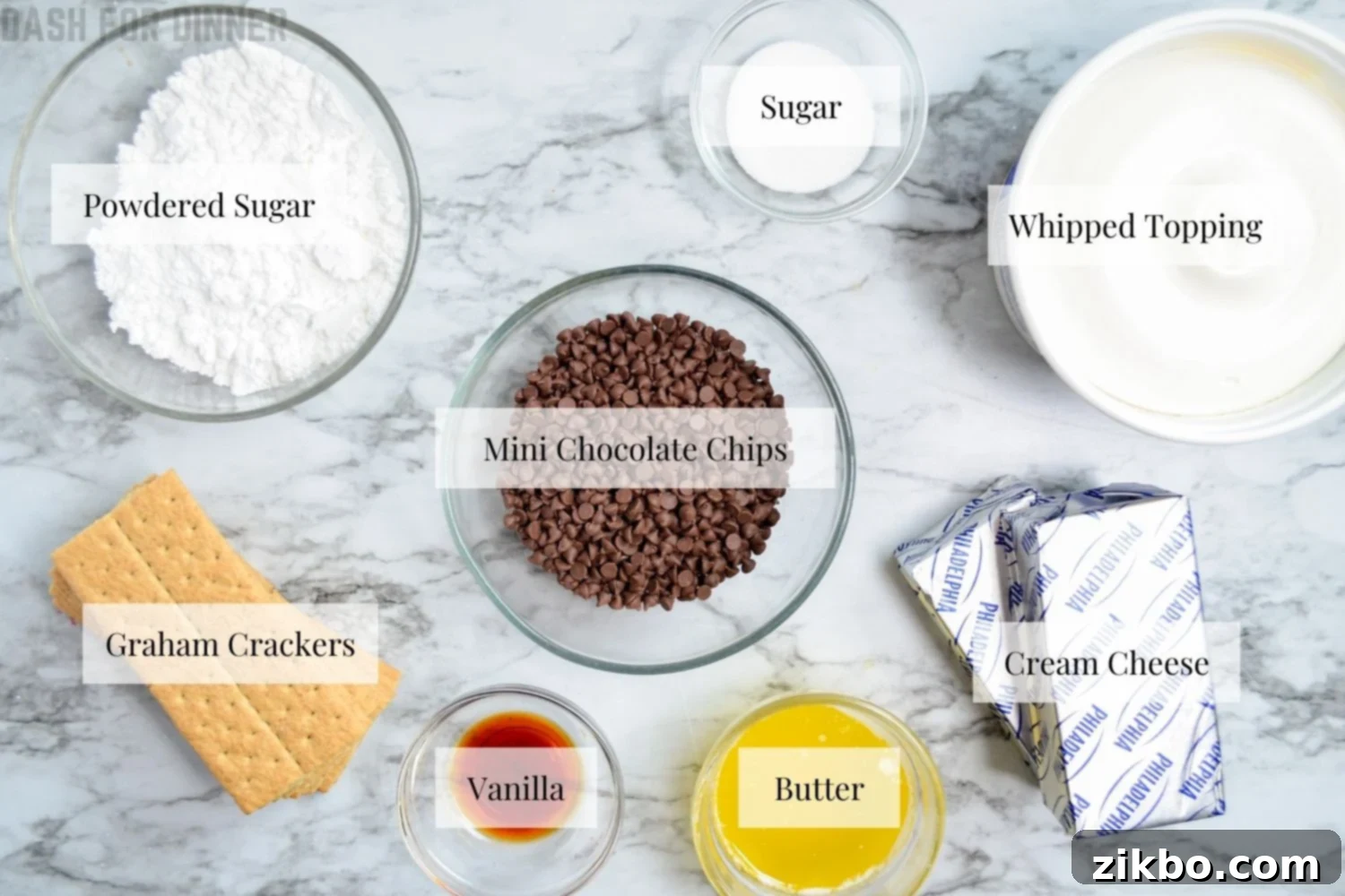 Ingredients for No Bake Chocolate Chip Cheesecake laid out on a table, including graham crackers, cream cheese, and chocolate chips.