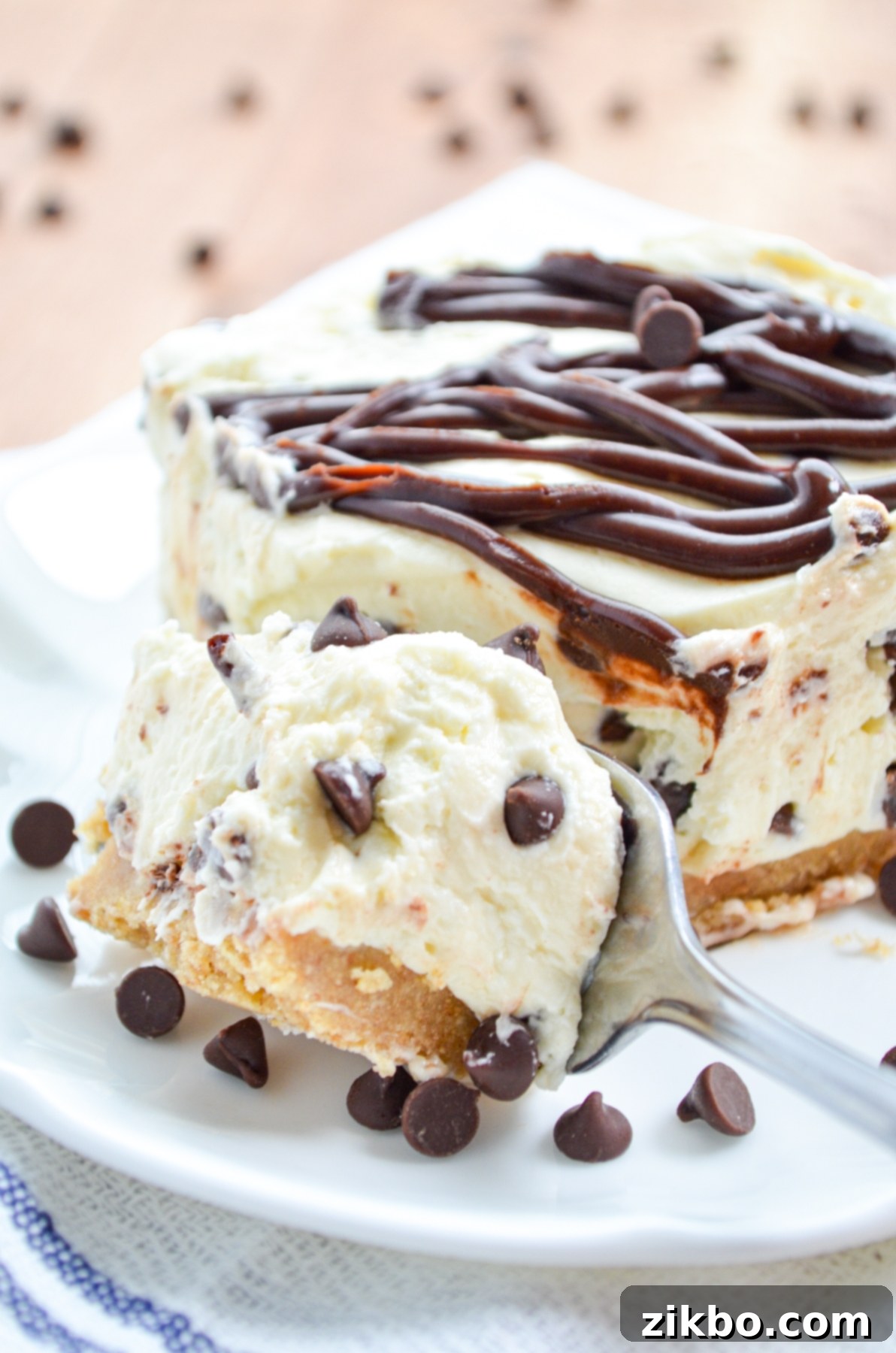 A fork taking a piece of no bake chocolate chip cheesecake, showcasing the creamy texture and chocolate chips within.
