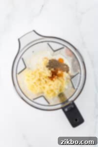 A blender filled with eggs, cottage cheese, seasonings, and shredded cheese.
