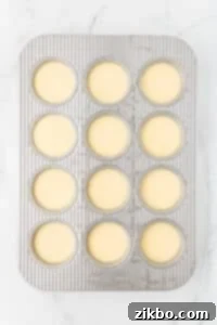 A muffin pan with all of the wells filled with an egg mixture.