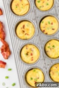 A muffin pan filled with egg bites and topped with bacon.