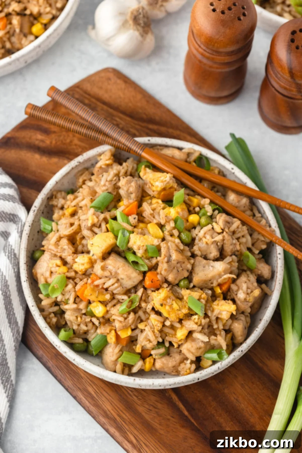 Signature Benihana Chicken Fried Rice 2 A bowl of chicken fried rice with a pair of chopsticks on the side.
