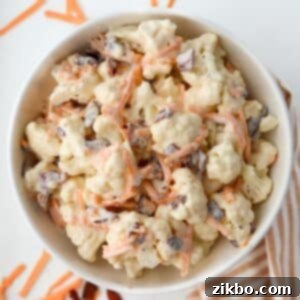 A bowl of cauliflower salad dotted with cheese and bacon.