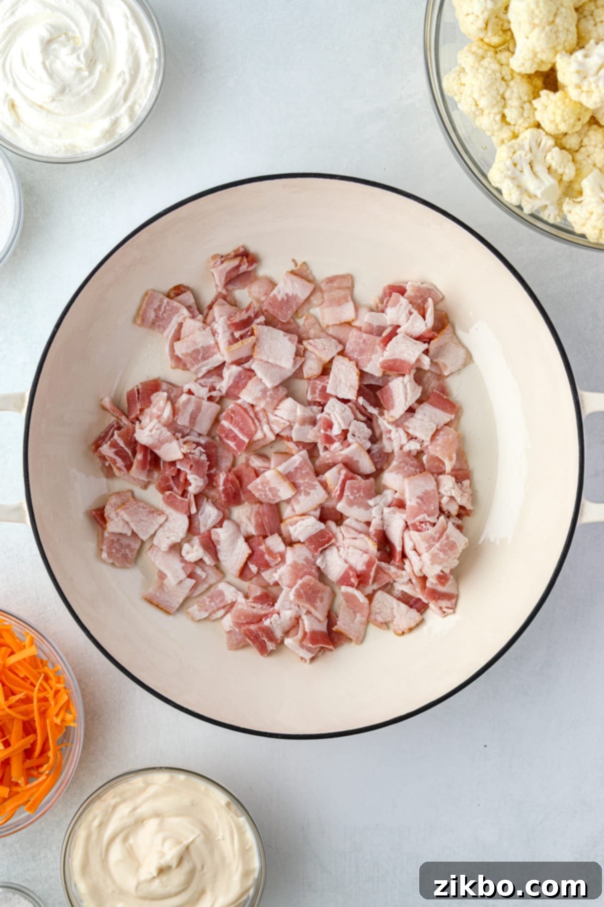 A skillet with raw bacon pieces chopped into small squares, ready to be cooked.