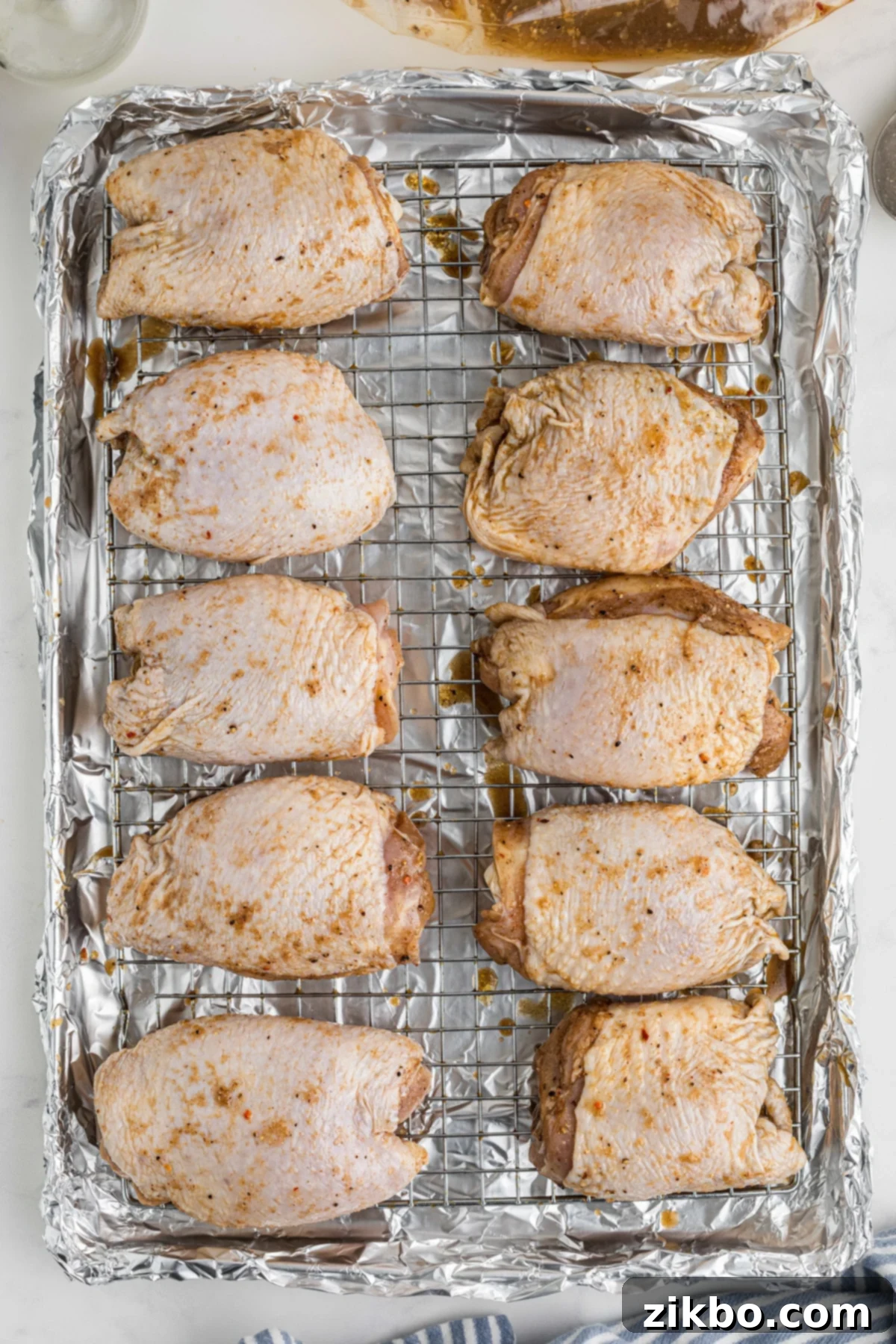 Step 4: Arranging marinated chicken thighs on a wire rack over a foil-lined baking sheet, spaced for even cooking.