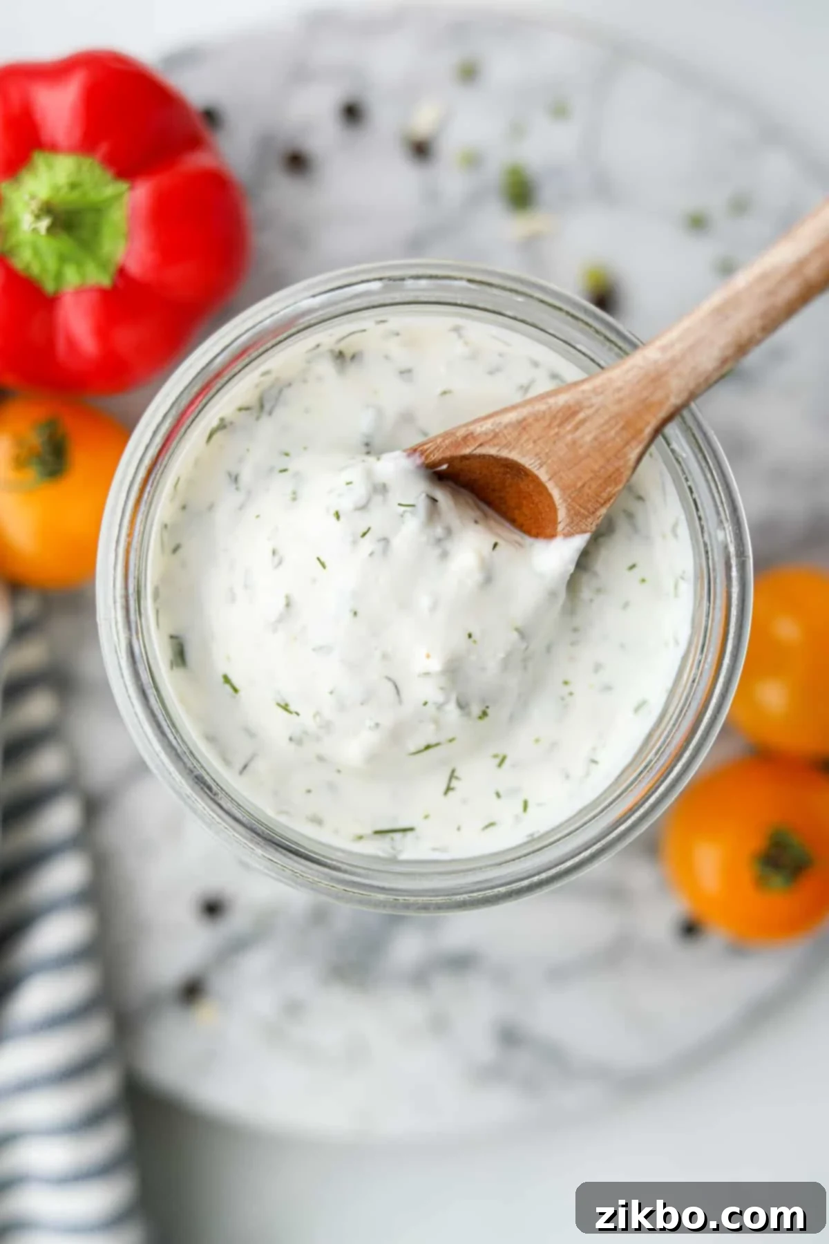 Zesty Greek Ranch Duo 2 Scooping creamy Greek Yogurt Ranch from a glass jar with a wooden spoon, showcasing its perfect texture for a dip.