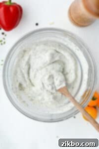 A wooden spoon stirring homemade ranch dressing in a bowl.