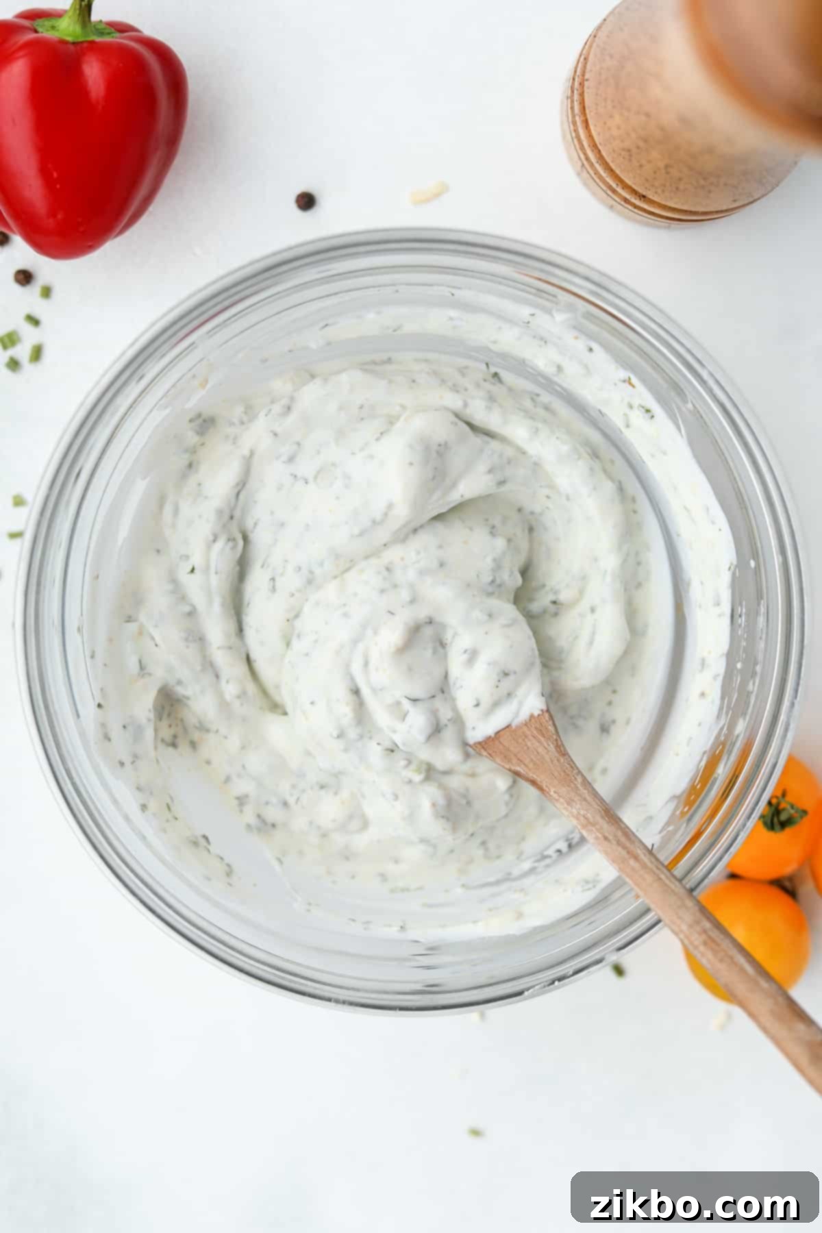 Zesty Greek Ranch Duo 6 A bowl of homemade Greek Yogurt Ranch dressing being continuously stirred with a wooden spoon to ensure a perfectly smooth and well-combined texture.