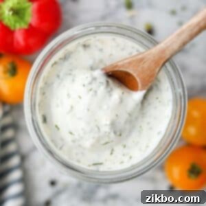 Zesty Greek Ranch Duo 10 Scooping ranch dressing from a glass jar with a wooden spoon.